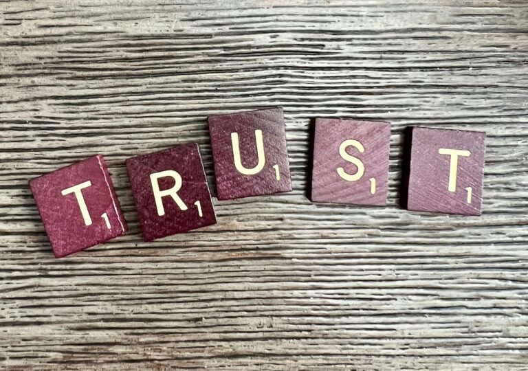 Daily Walk Devotion: Trust in God over worldly measures with scrabble tiles spelling trust on a wood.