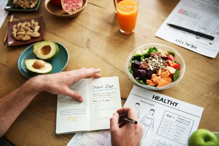 Healthy salad bowl, diet plan notes, and orange juice on wooden table.
