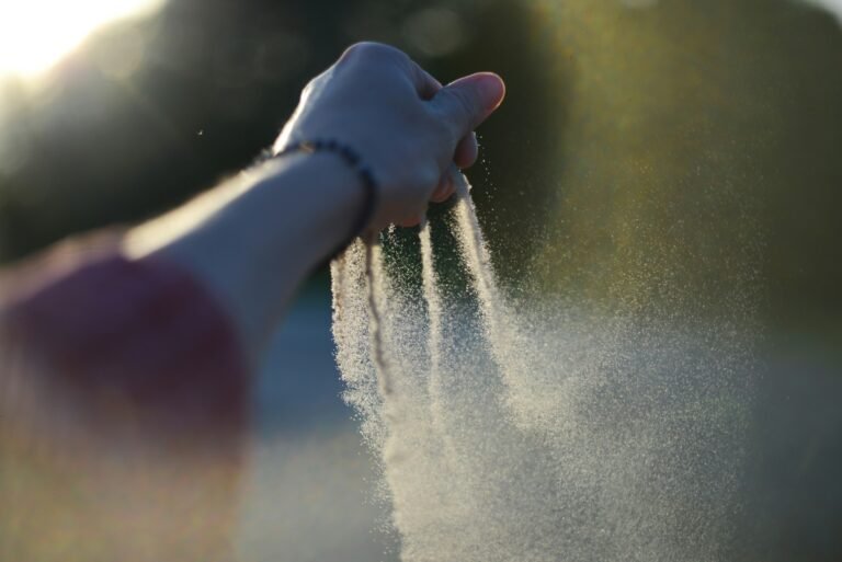 Hands releasing a mist of water in sunlight, outdoor scene.