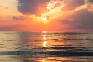 Daily Walk Devotion: sunrise over calm ocean with warm colors.