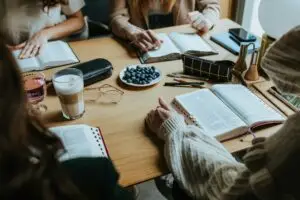 Small group studying Bible at table with notebooks and blueberries.