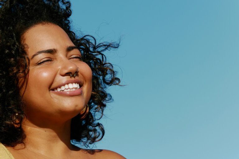 Smiling woman outdoors with clear blue sky background.